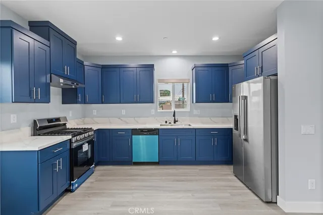 a kitchen with stainless steel appliances granite countertop wooden cabinets a sink dishwasher a stove and a refrigerator with wooden floor