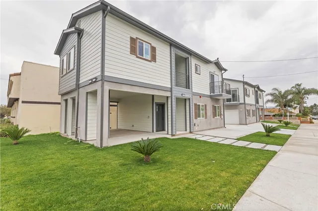 a view of a white house next to a yard with big trees