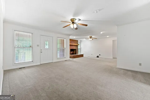 an empty room with chandelier fan and windows