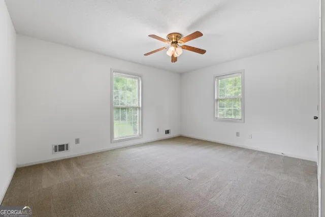 en empty room with windows and chandelier fan