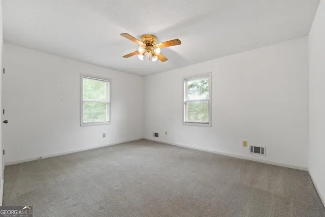 an empty room with windows and chandelier fan