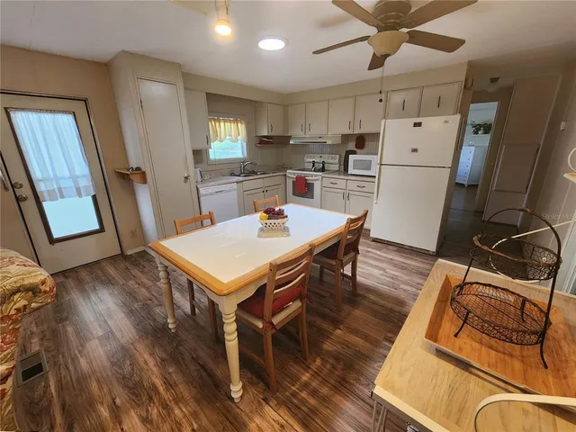 a kitchen with stainless steel appliances a stove a refrigerator a sink a dining table and chairs with wooden floor