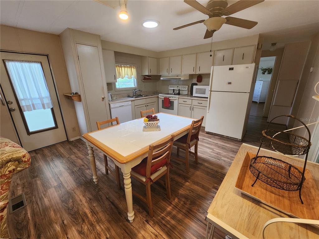 6400 Taylor/trout Road, Unit 96 Punta Gorda, FL 33950 - Photo 7 of 17 a kitchen with stainless steel appliances a stove a refrigerator a sink a dining table and chairs with wooden floor
