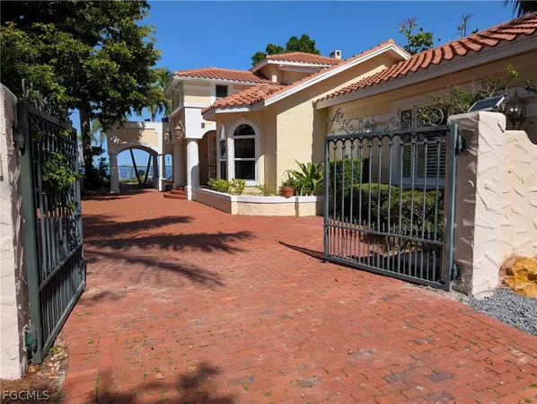 a view of a white house with a large tree and wooden fence