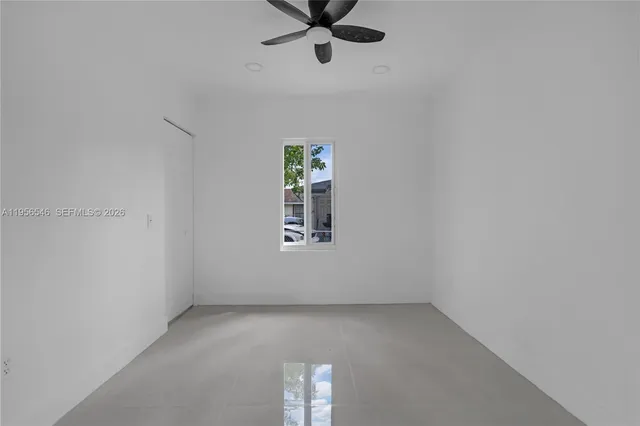 an empty room with a window and a ceiling fan