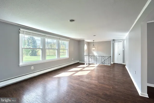 a view of empty room with wooden floor and window