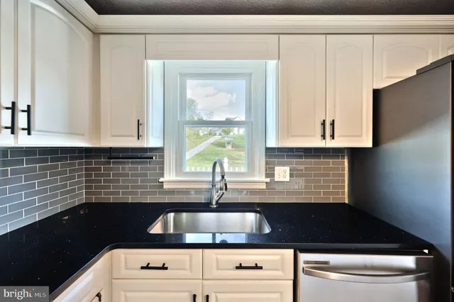 a kitchen that has a sink and a stove with wooden floor