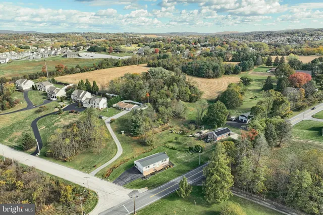 an aerial view of a residential houses with outdoor space and trees