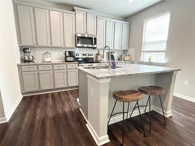 a kitchen with stainless steel appliances granite countertop a stove a sink dishwasher and a microwave oven with wooden floor