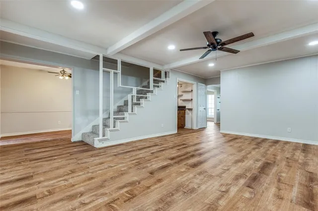 a view of an empty room with wooden floor and a ceiling fan