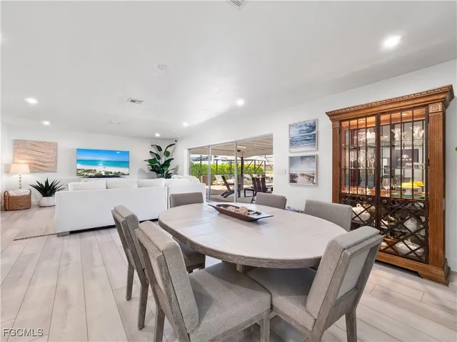 a living room with stainless steel appliances furniture a dining table and kitchen view
