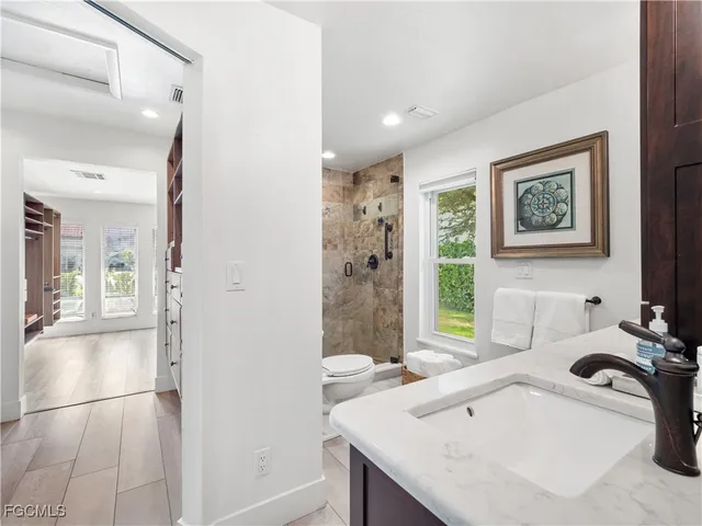a bathroom with a granite countertop sink a toilet and shower