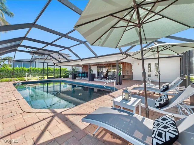 a view of a swimming pool with a lounge chair and palm trees