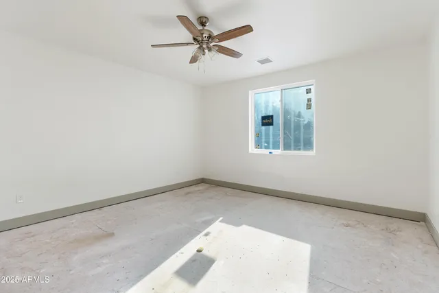 an empty room with a window and a ceiling fan