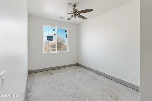 an empty room with windows and fan