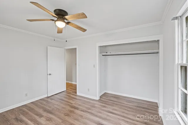 a view of empty room with wooden floor and fan