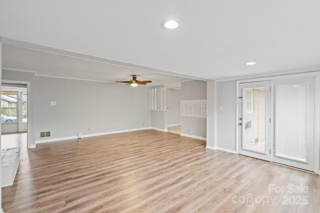 a view of an empty room with wooden floor and windows