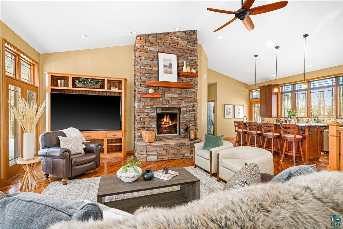 92598 Spells Road Sturgeon Lake, MN 55783 - Photo 10 of 60 Living area featuring wood finished floors, a stone fireplace, vaulted ceiling, a ceiling fan, and recessed lighting