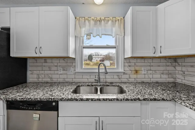 a kitchen with granite countertop a sink and a white wooden cabinets