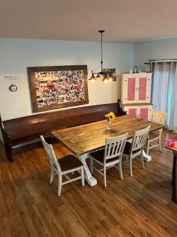 a room with wooden floor pool table and chairs