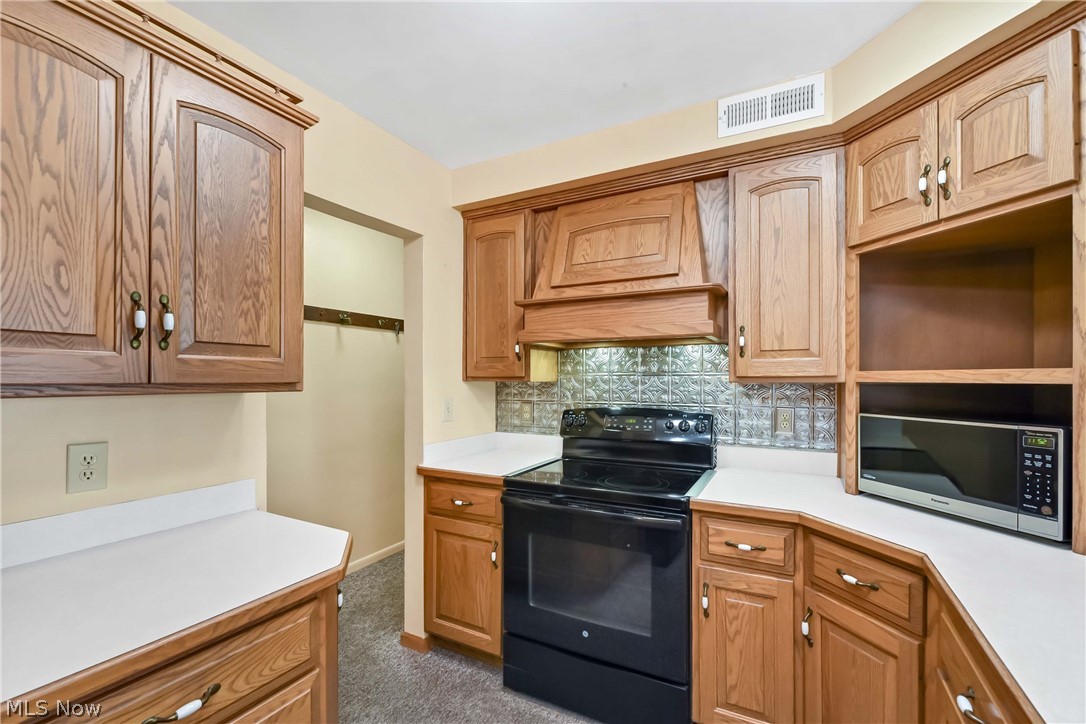 3690 Long Road Avon, OH 44011 - Photo 14 of 41 Kitchen featuring backsplash, black range with electric cooktop, custom exhaust hood, and carpet