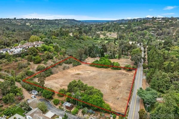 an aerial view of residential houses with outdoor space and trees