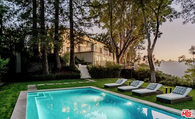 a view of a backyard with swimming pool and green space
