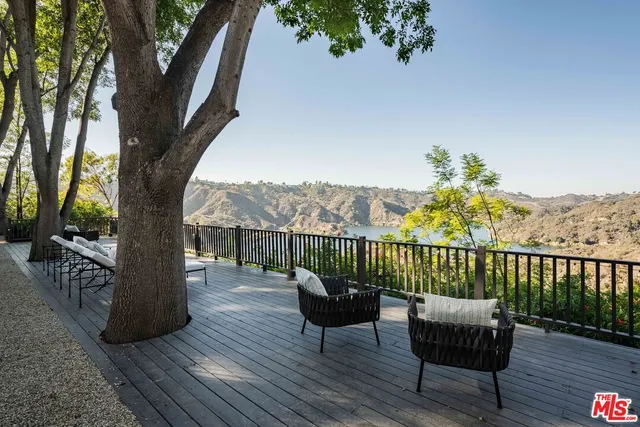 a view of a balcony with chairs and wooden fence