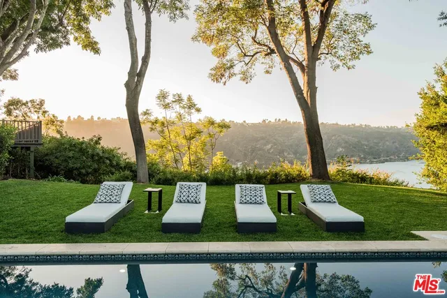 a view of a swimming pool with lounge chairs in back yard