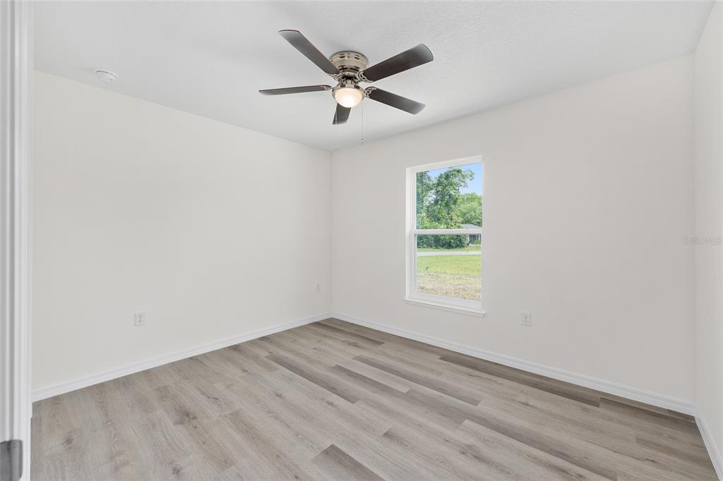 13019 Northeast 7th Loop Silver Springs, FL 34488 - Photo 26 of 35 an empty room with wooden floor ceiling fan and windows