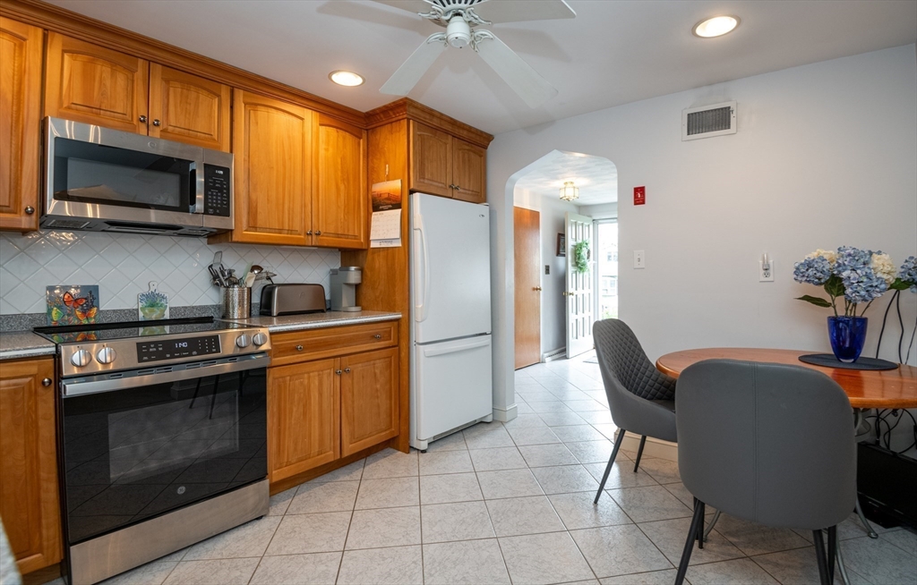 6 Janice Lane Stoneham, MA 02180 - Photo 13 of 35 a kitchen with stainless steel appliances granite countertop a stove a refrigerator a sink dishwasher a dining table and chairs with wooden floor