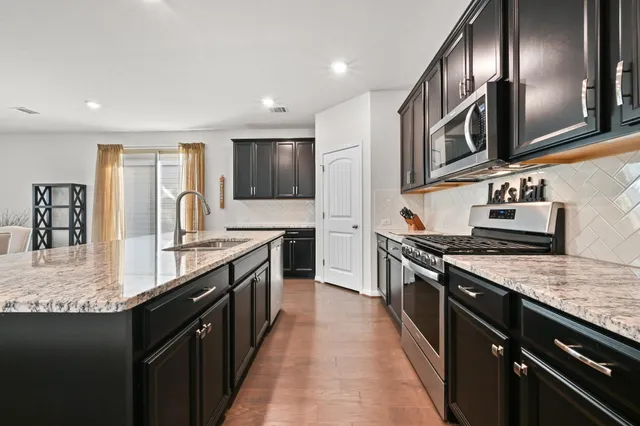 a large kitchen with stainless steel appliances granite countertop a stove a sink and a microwave