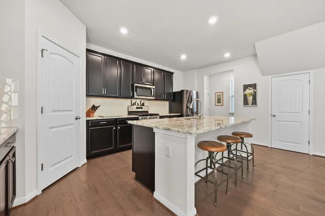 a kitchen with kitchen island granite countertop wooden cabinets and stainless steel appliances