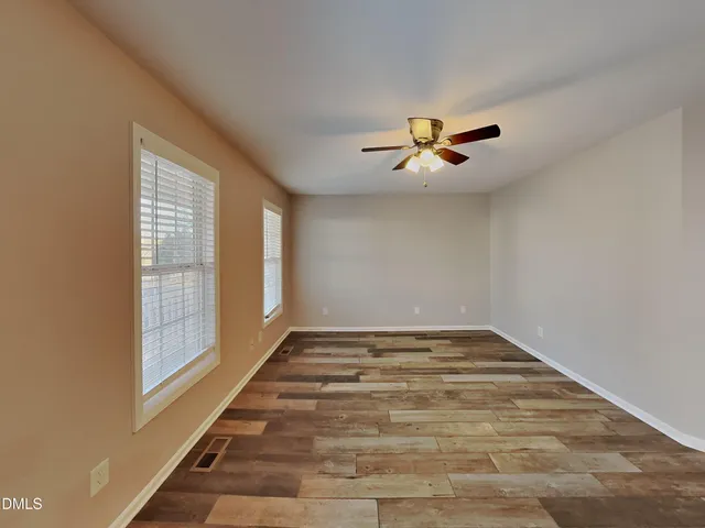 a view of an empty room with window and chandelier fan
