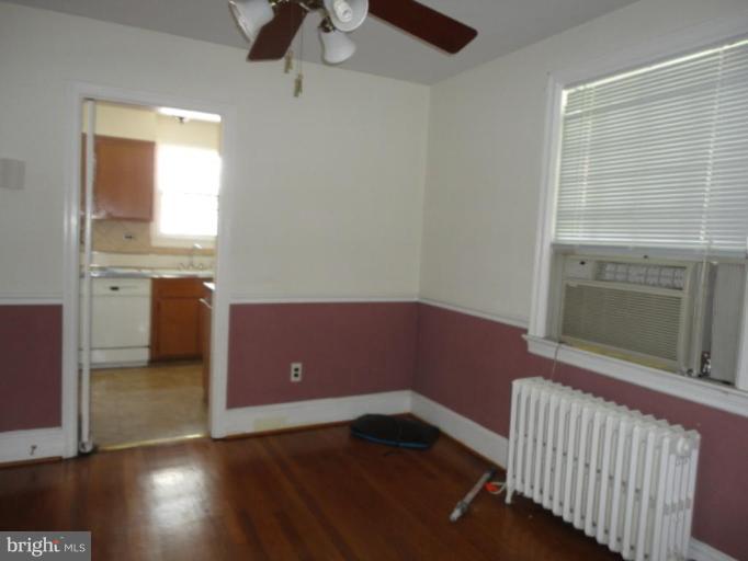 10008 Sutherland Road Silver Spring, MD 20901 - Photo 3 of 9 an empty room with wooden floor cabinet and windows
