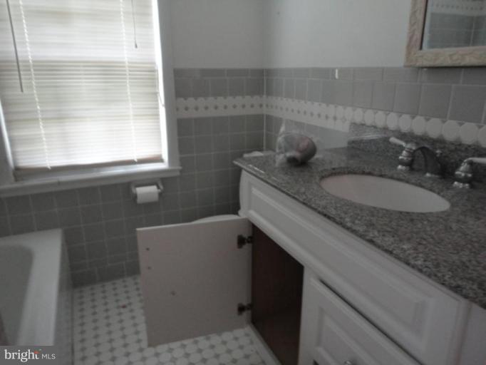 10008 Sutherland Road Silver Spring, MD 20901 - Photo 8 of 9 a bathroom with a granite countertop sink a toilet a mirror and window