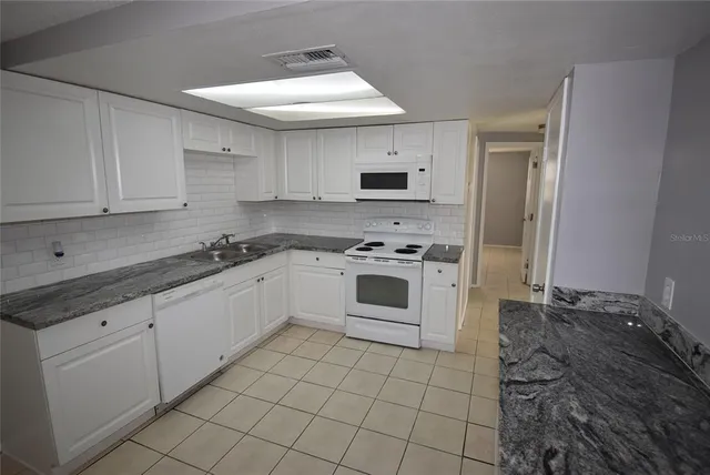 a white kitchen with a stove top oven and cabinets