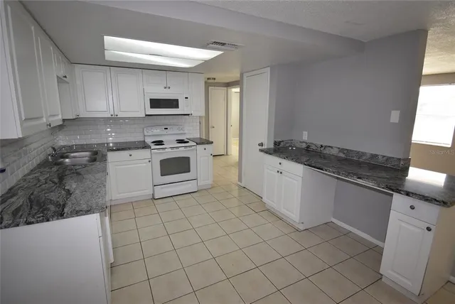a kitchen with granite countertop a sink stove and cabinets