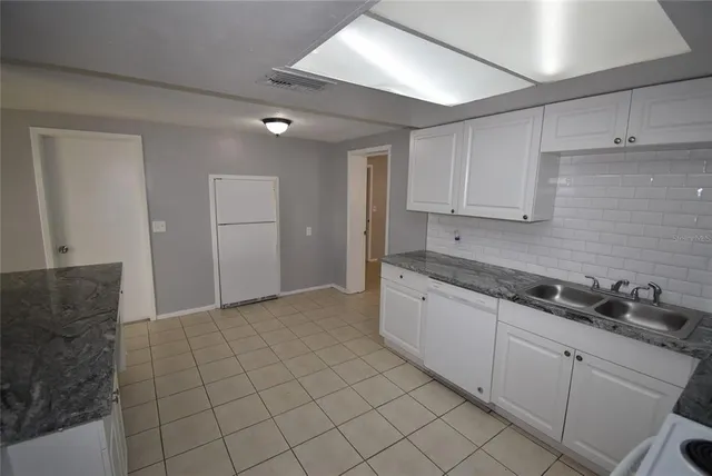 a kitchen with granite countertop white cabinets and stainless steel appliances