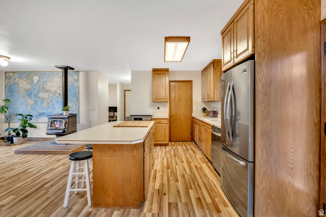 887 Village Way Alpine, UT 84004 - Photo 16 of 28 Kitchen featuring light countertops, stainless steel appliances, a breakfast bar area, light wood-style floors, and a wood stove