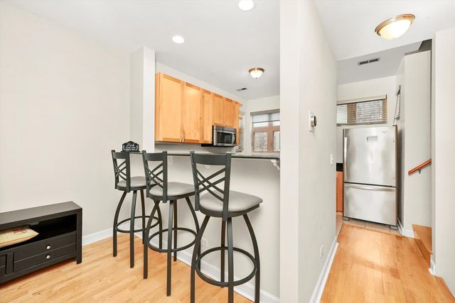 a kitchen with stainless steel appliances a refrigerator a stove a dining table and chairs with wooden floor