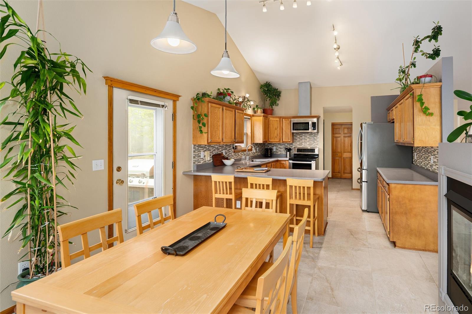 11163 Conifer Mountain Road Conifer, CO 80433 - Photo 4 of 46 a kitchen with stainless steel appliances kitchen island granite countertop a stove a sink a refrigerator and a dining table with wooden floor