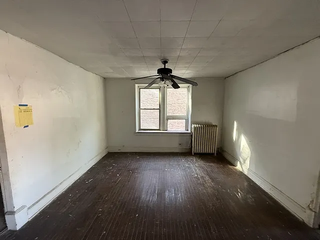 an empty room with wooden floor chandelier and windows