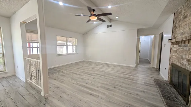 a view of an empty room with a window and wooden floor