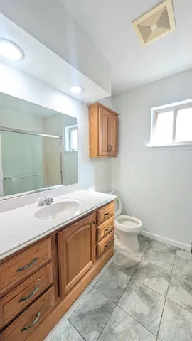 an empty room with a chandelier fan and wooden floor
