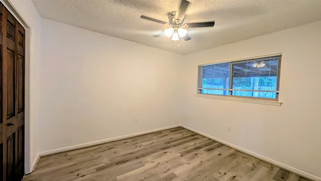 an empty room with wooden floor chandelier and window