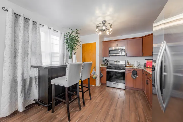 a kitchen with granite countertop a refrigerator a stove a sink dishwasher a dining table and chairs with wooden floor