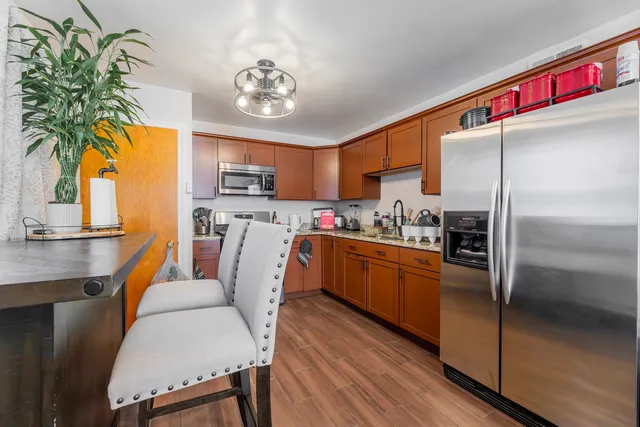 a kitchen with stainless steel appliances granite countertop a refrigerator a stove and a wooden floors