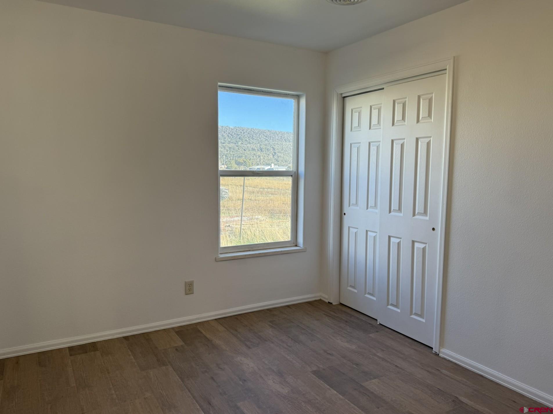 18358 Surface Creek Road Cedaredge, CO 81413 - Photo 11 of 26 an empty room with wooden floor and windows