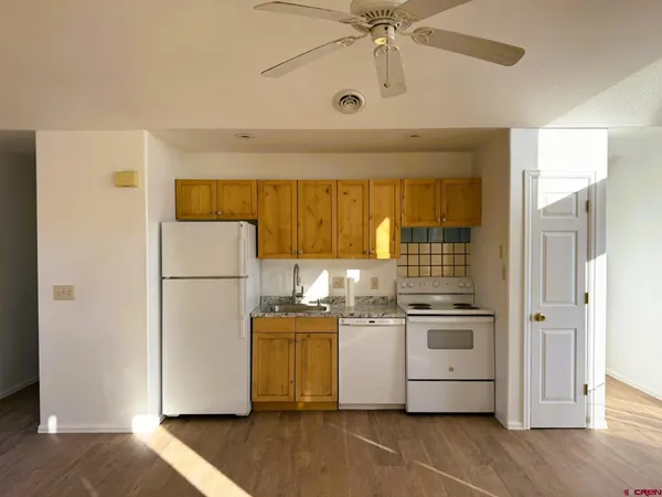 a kitchen with a refrigerator a stove and a wooden floor